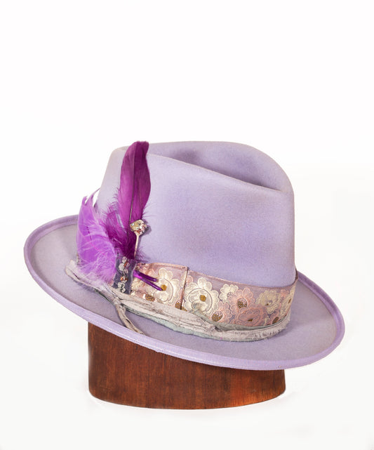 Lavender Kid is a custom dyed beaver fur felt hat with a vintage brocade hat band. A handmade silver and glass bead hat pin. A branded leather sweat band and silk lining. All inspired by the lavender flower.